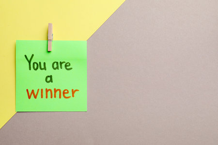 Sticky note with phrase You Are A Winner on color background, top view. Space for textの写真素材