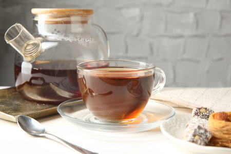 Tasty tea in glass cup, teapot and Turkish desserts on white table against gray textured background, closeupの写真素材