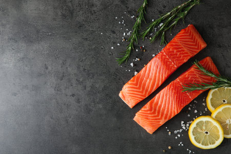 Pieces of salmon fillet and spices on gray table, flat lay. Space for text