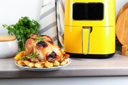 Tasty grilled chicken with rosemary and vegetables on wooden tableの写真素材