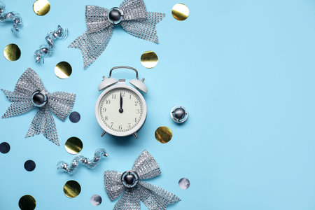 New Year celebration. Alarm clock and festive decor on light blue background, flat lay. Space for...