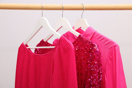 Different stylish clothes hanging on rack near light wall indoors, closeupの写真素材