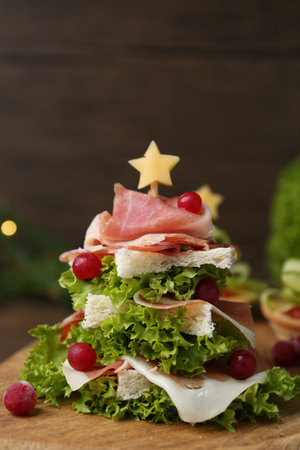 Christmas tree shaped snack made with lettuce, ham, and berries on wooden table, closeupの写真素材