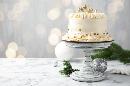 Delicious cake with Christmas decor on white marble table against blurred lights. Space for textの写真素材