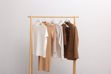 Different stylish clothes hanging on rack near light wall indoorsの写真素材