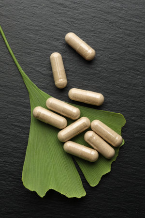 Ginkgo biloba leaf and pills on dark textured table, flat layの写真素材