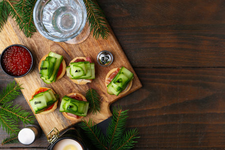 Christmas trees made with cucumber, red caviar, ham and festive decor on wooden table, flat lay. Space for textの写真素材