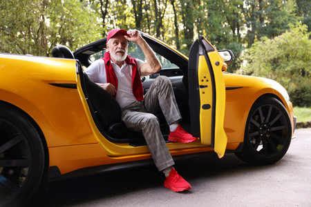 Stylish senior man in modern cabriolet outdoors
