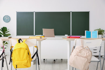Green chalkboard, desks and chairs in classroom. Mockup for designの写真素材