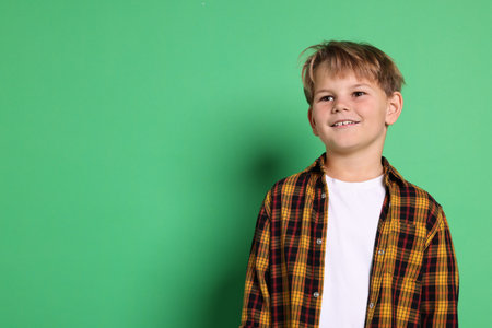 Portrait of cute boy on green background, space for textの写真素材