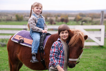 Equine assisted therapy. Cute children with beautiful pony outdoors. Lovely domesticated petの写真素材