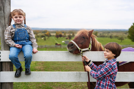 Equine assisted therapy. Cute children with beautiful pony at paddock. Lovely domesticated petの写真素材