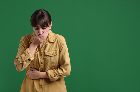Young woman suffering from stomachache and nausea on green background, space for textの写真素材