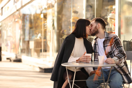 Affectionate couple kissing in outdoor cafe. Space for textの写真素材