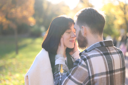 Cute couple kissing in sunny autumn park. Space for textの写真素材