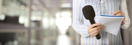 Journalist with microphone writing in notebook indoors, closeup. Banner designの写真素材