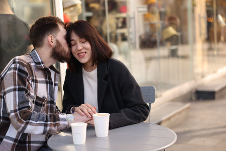 Affectionate couple holding hands in outdoor cafe. Space for textの写真素材