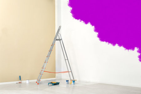 Decorator's tools and paint on floor in room. Wall partly painted in purple color. Interior renovationの写真素材