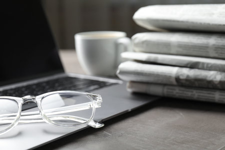 Newspapers, laptop and glasses on gray table, closeupの写真素材
