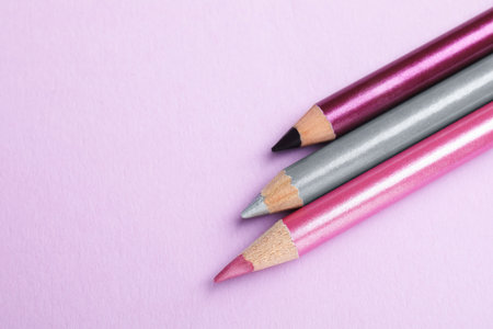 Color eye pencils on pink background, flat lay. Space for textの写真素材