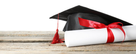 Diploma and graduation hat on wooden table against white backgroundの写真素材