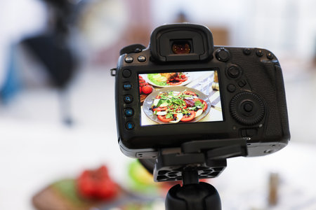 Shooting caprese salad at table in studio, focus on camera screen. Professional food photographyの写真素材