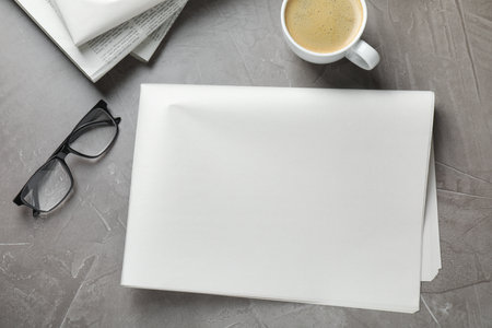Newspapers, coffee and glasses on gray table, flat lay. Mockup for designの写真素材