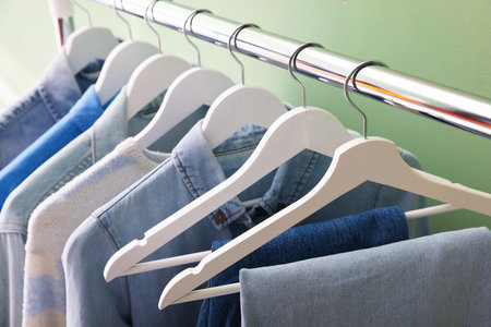 Different stylish clothes hanging on rack against green background, closeupの写真素材