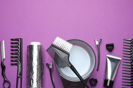 Professional tools and products for hair dyeing on purple background, flat lay. Space for textの写真素材