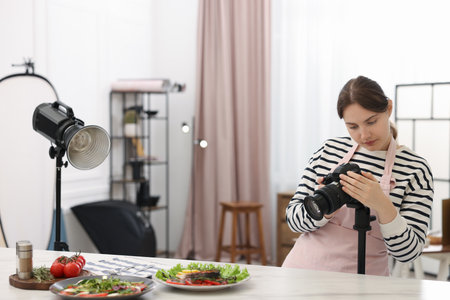 Woman taking picture of meal at table in kitchen, space for text. Professional food photographyの写真素材