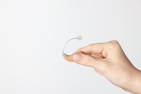 Woman with hearing aid on light background, closeup. Space for textの写真素材