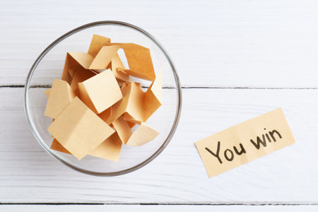 Note with text You Win and paper pieces on white wooden table, flat layの写真素材