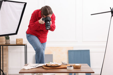 Woman taking picture of croissants at table in studio, space for text. Professional food photographyの写真素材