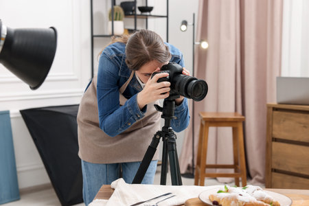 Woman taking picture of croissants at table in studio. Professional food photographyの写真素材