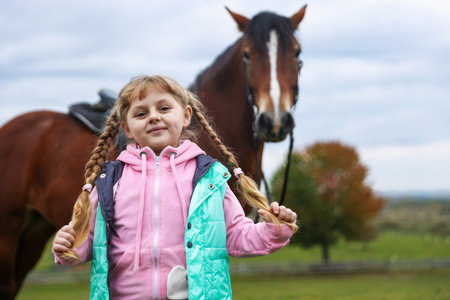 Equine assisted therapy. Little girl and beautiful horse outdoors, selective focus.の写真素材