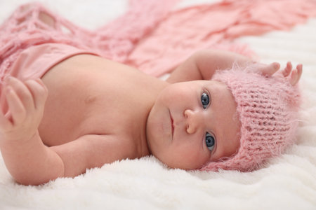 Portrait of cute newborn baby in pink hat and blanket lying on bed, closeupの写真素材