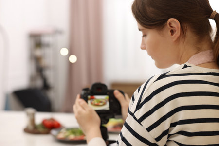Woman taking picture of meal at table in studio, selective focus with space for text. Professional food photographyの写真素材