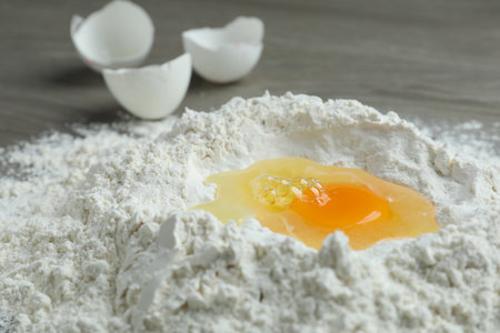 Broken eggs, yolk and flour on wooden table, closeupの写真素材