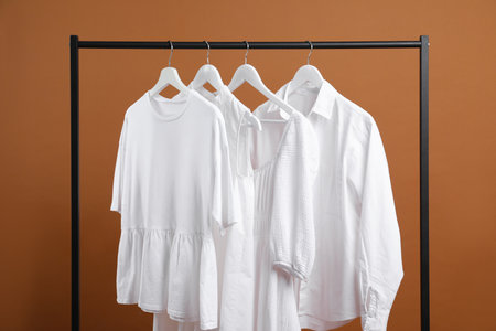 Different clothes hanging on rack against brown backgroundの写真素材