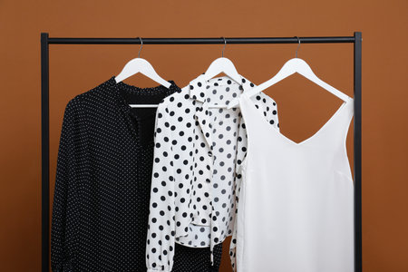 Different clothes hanging on rack against brown backgroundの写真素材