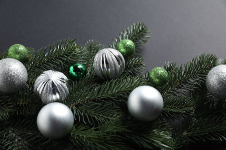 Christmas tree branches with shiny baubles on dark background, closeupの写真素材