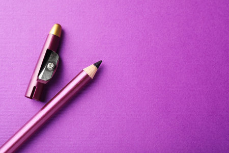 Eye pencil and cap with sharpener on purple background, top view. Space for textの写真素材