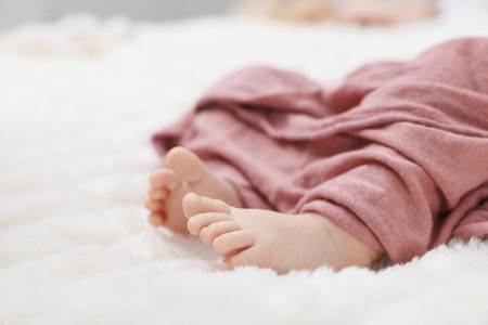 Newborn baby covering with pink blanket on bed, closeup. Space for textの写真素材