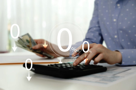 Woman with money using calculator at table, closeup. 0 percent representing zero commissionの写真素材