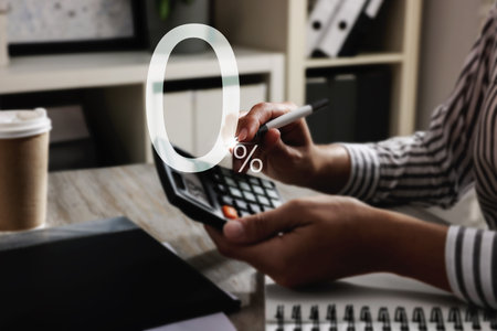 Woman using calculator at table, closeup. 0 percent representing zero commissionの写真素材