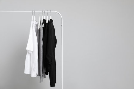 Different clothes hanging on rack against gray background, space for textの写真素材