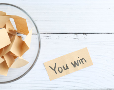 Note with text You Win and paper pieces on white wooden table, flat layの写真素材