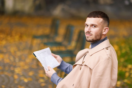 Young man reading newspaper outdoors. Space for textの写真素材
