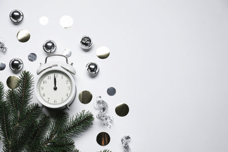 New Year celebration. Alarm clock and festive decor on light gray background, flat lay. Space for textの写真素材