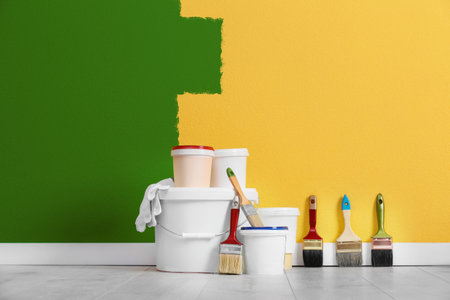 Decorator's tools and paint on floor in room. Wall partly painted in yellow color. Interior renovationの写真素材